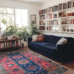 A beautifully styled living room featuring a vintage hand-knotted area rug with vibrant colors, perfect for enhancing any space. The rug's intricate Persian design adds elegance, while its 8x10 size is ideal for living room settings. Surrounded by lush plants, a navy blue sofa, and a bookshelf, this rug is an exquisite choice for those seeking rugs for living room spaces.
