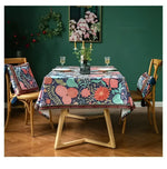 Vintage velvet floral throw pillow with tassels, enhancing a beautifully set dining table with a floral tablecloth and a green wall background.