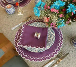 Overhead violet vigor placemat — purple scalloped white-dot border, blue floral plate, flat napkin, teal florals