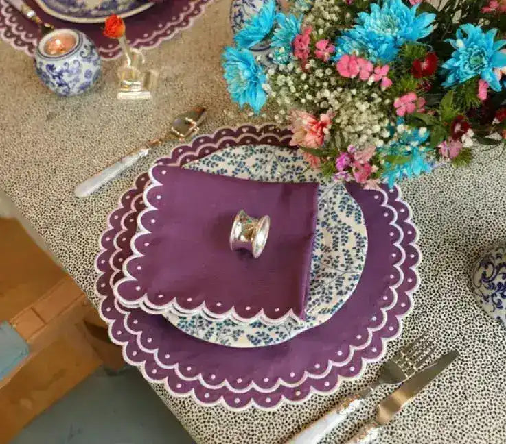 Overhead violet vigor placemat — purple scalloped white-dot border, blue floral plate, flat napkin, teal florals