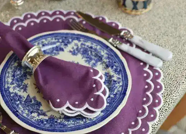 Side-angle violet vigor placemat — purple scalloped white-dot edge, floral china, purple napkin and silver ring