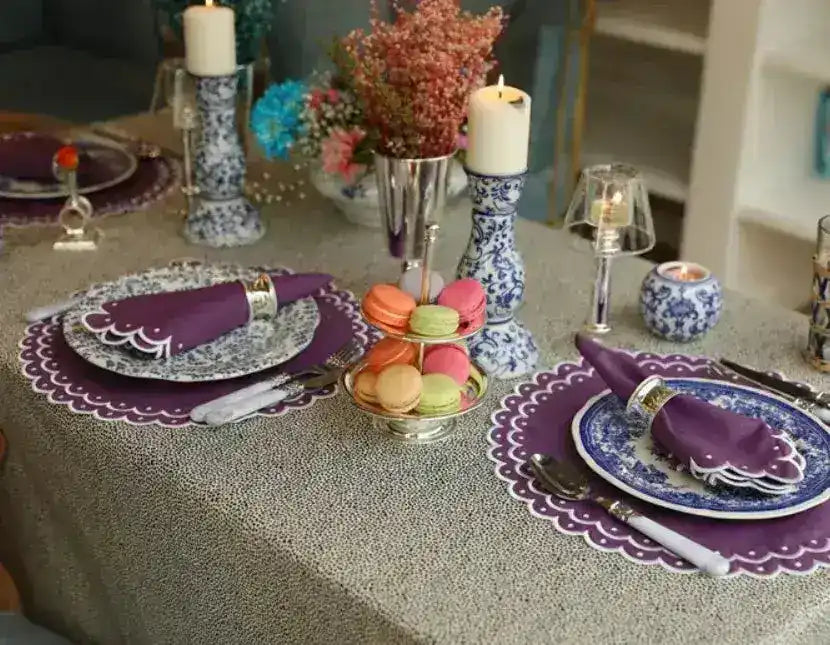 Table with violet vigor placemats, floral plates, purple napkins, macaron tower, blue candlesticks and dried flowers