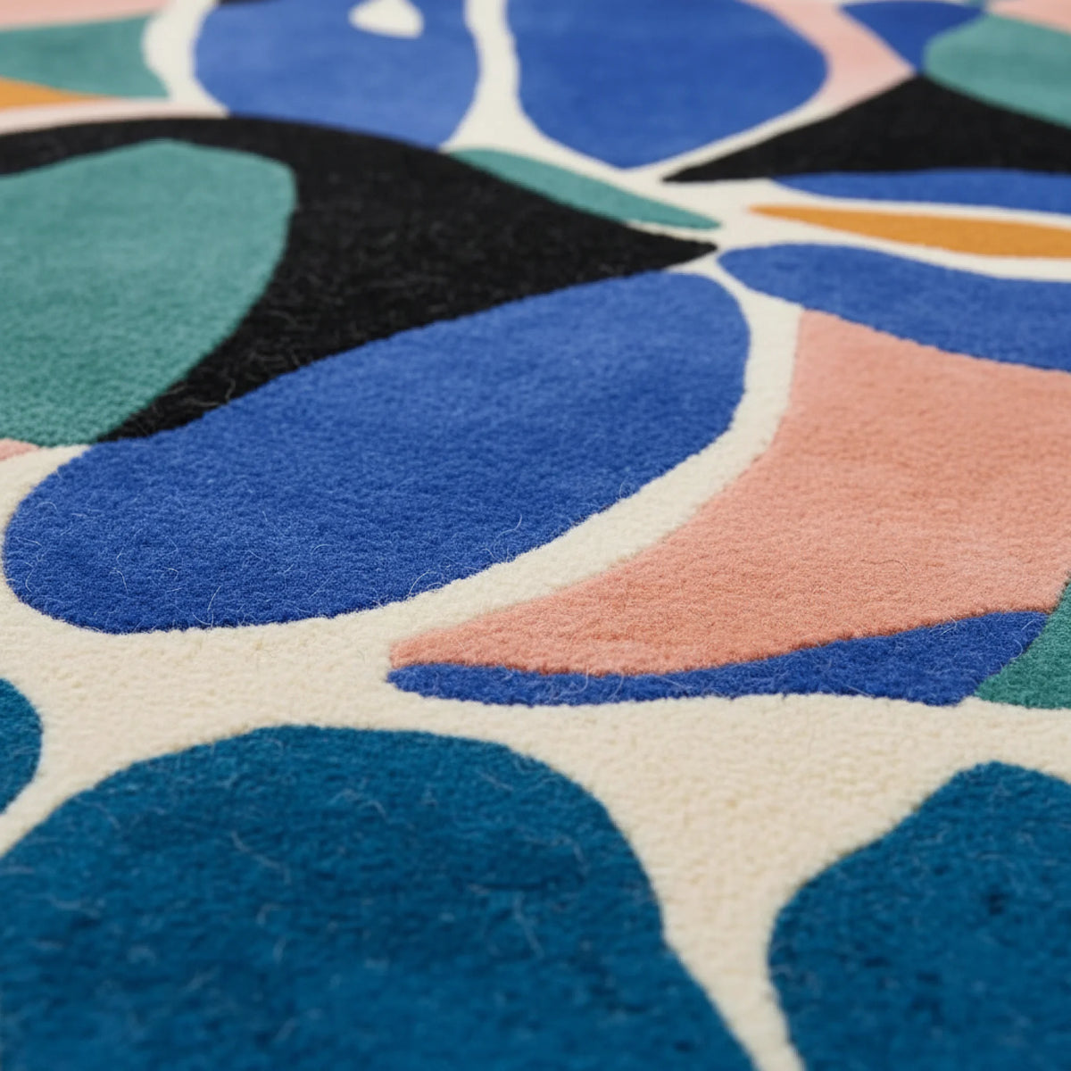 Close-up of a colorful abstract patterned rug with blue, green, and pink shapes.