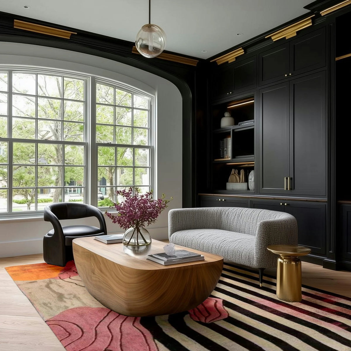 vivid shapes hand tufted viscose rug in a dark-paneled room with arched bay window, curved grey sofa and oval wood coffee table