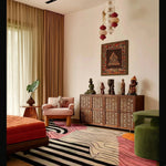 vivid shapes hand tufted viscose rug in an eclectic room with carved wooden sideboard, statues, orange ottoman and lantern light