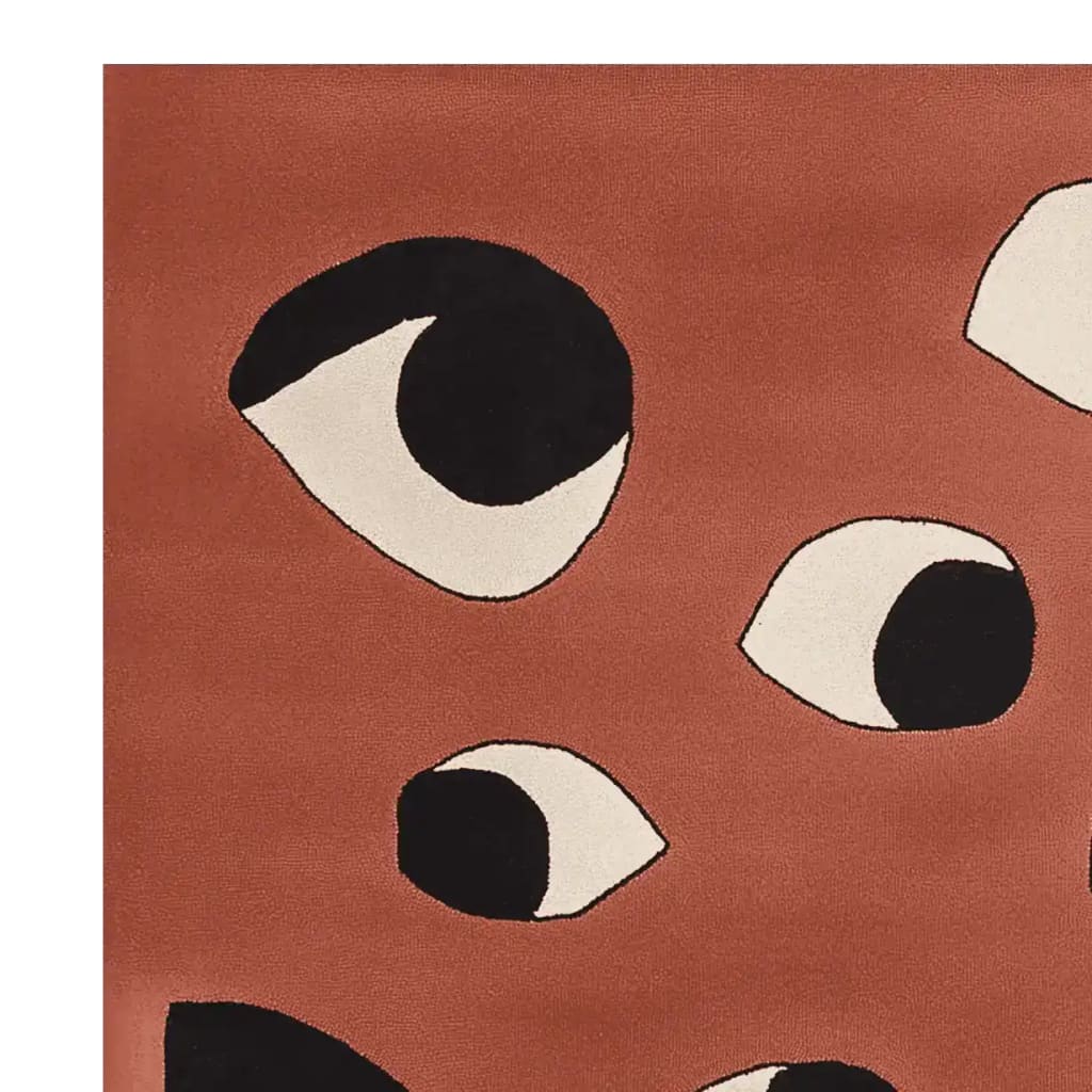 Contemporary hand-tufted area rug with a unique abstract eye pattern in black and white on a warm terracotta background, perfect for adding a modern touch to any living room. Made from high-quality wool, this rug combines both style and comfort.
