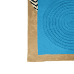 Corner of a blue and beige rug with circular pattern