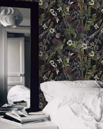 Whimsical vintage garden wallpaper with detailed daisies and thistles on black in a moody bedroom with white linens