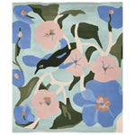 A beautifully designed area rug titled 'Whispering Garden Muse Hand Tufted Rug', featuring a vibrant floral pattern with pink and blue flowers and a black bird. This wool rug is perfect for adding a touch of contemporary style to any living room.