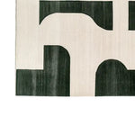 Top view of the Whispering Sands Glow Knotted Wool Rug, featuring an abstract geometric design with dark green shapes on a light background. Perfect as a large living room rug, this contemporary wool rug adds elegance and style to any living room area.