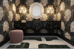 Decorative interior with geometric green rug, floral wallpaper, a round mirror, and a textured ottoman.