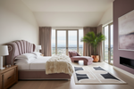 Modern bedroom with a large bed, geometric rug, chaise lounge, and city view.