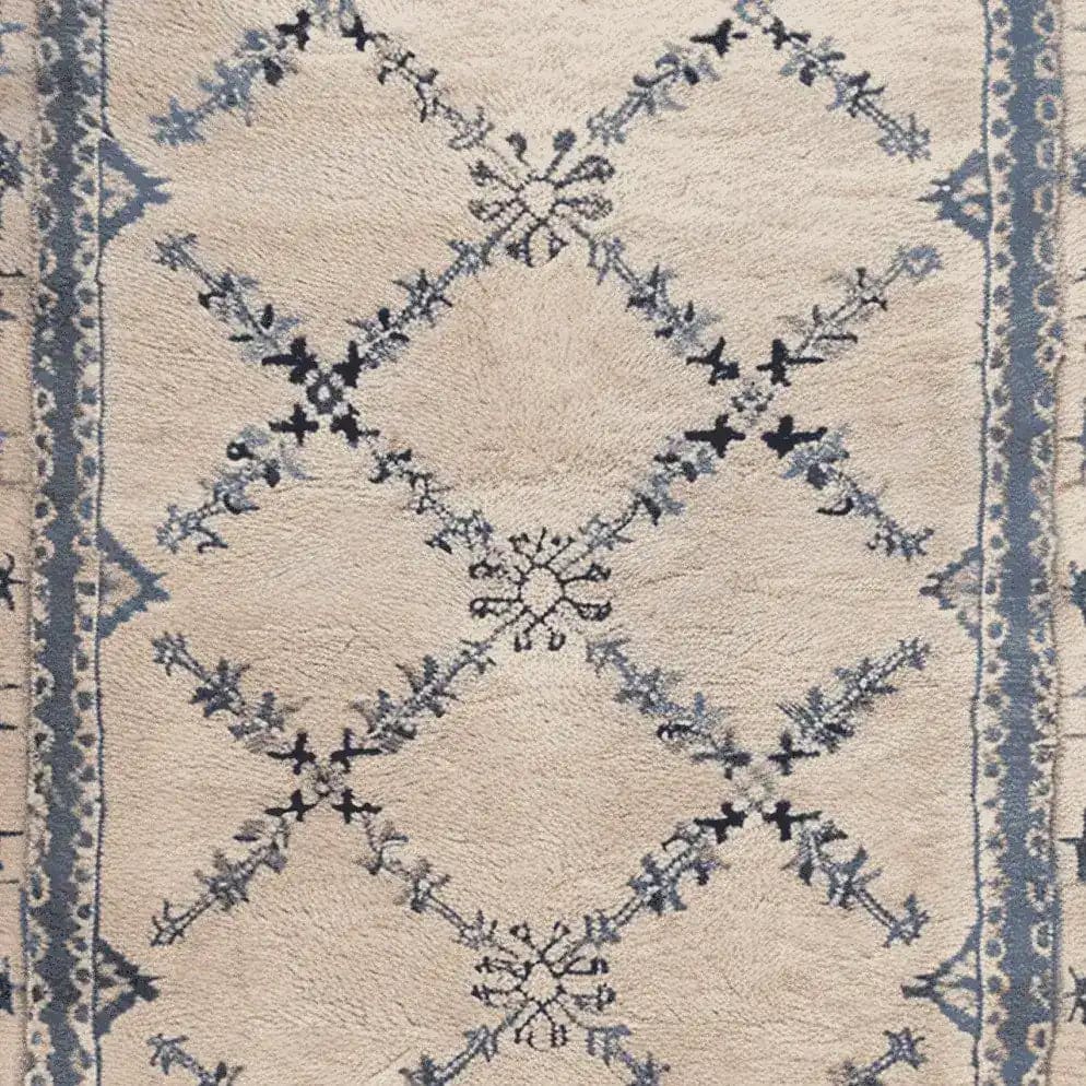 Close-up of the Whispering Vines Hand Knotted Rug, showcasing its intricate wool design with blue and black vine patterns on a cream background. Perfect as an area rug, this vintage-inspired piece is ideal for adding elegance to living room spaces.