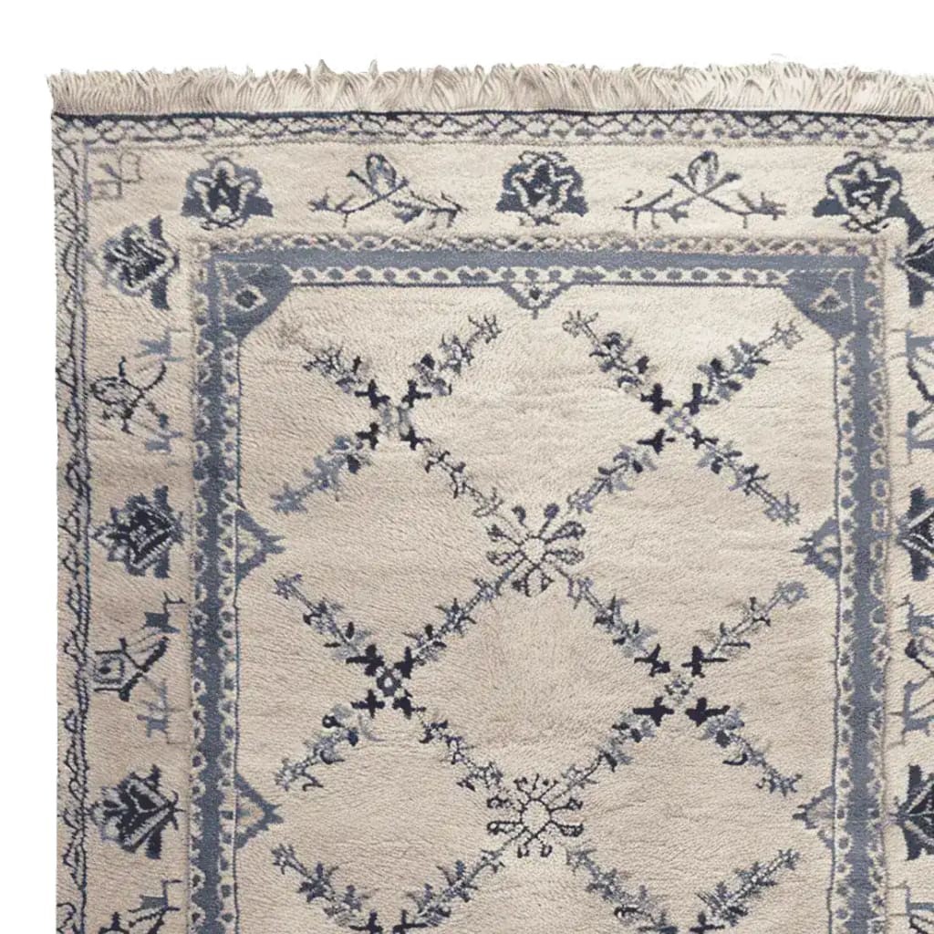 Close-up view of the Whispering Vines Hand Knotted Rug, showcasing its intricate floral and geometric patterns. This wool area rug, perfect for living rooms, features a vintage design in soft blue and cream tones, exemplifying elegance and sophistication.