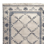 Close-up view of the Whispering Vines Hand Knotted Rug, showcasing its intricate floral and geometric patterns. This wool area rug, perfect for living rooms, features a vintage design in soft blue and cream tones, exemplifying elegance and sophistication.