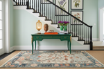 Staircase with a green console table, decorative items, and a floral rug.