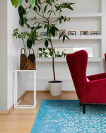 Elegant living room featuring a White Bloom Elegant Hand Tufted Viscose Rug in blue. This area rug adds a touch of vintage charm with its intricate design, perfect for large living room spaces. The red armchair and indoor plant complement the rug beautifully, creating a cozy and stylish atmosphere.