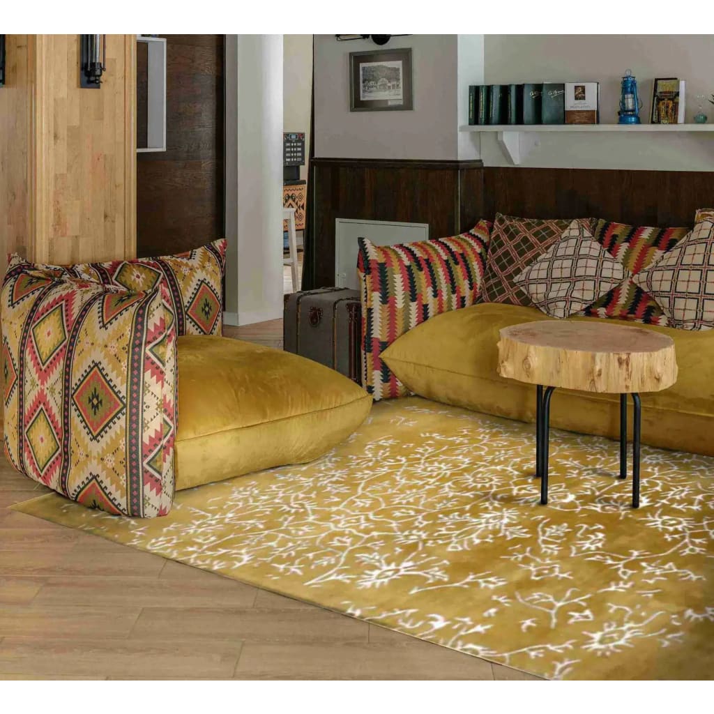 This elegant area rug, titled 'White Bloom Elegant Hand Tufted Viscose Rug - Golden', graces a stylish living room setting. Its intricate patterns and golden hues provide a vintage charm, making it an ideal choice for large living room rugs. Perfect for adding warmth and sophistication, this wool rug complements the vibrant cushions and natural wood accents, creating a cozy and inviting space.