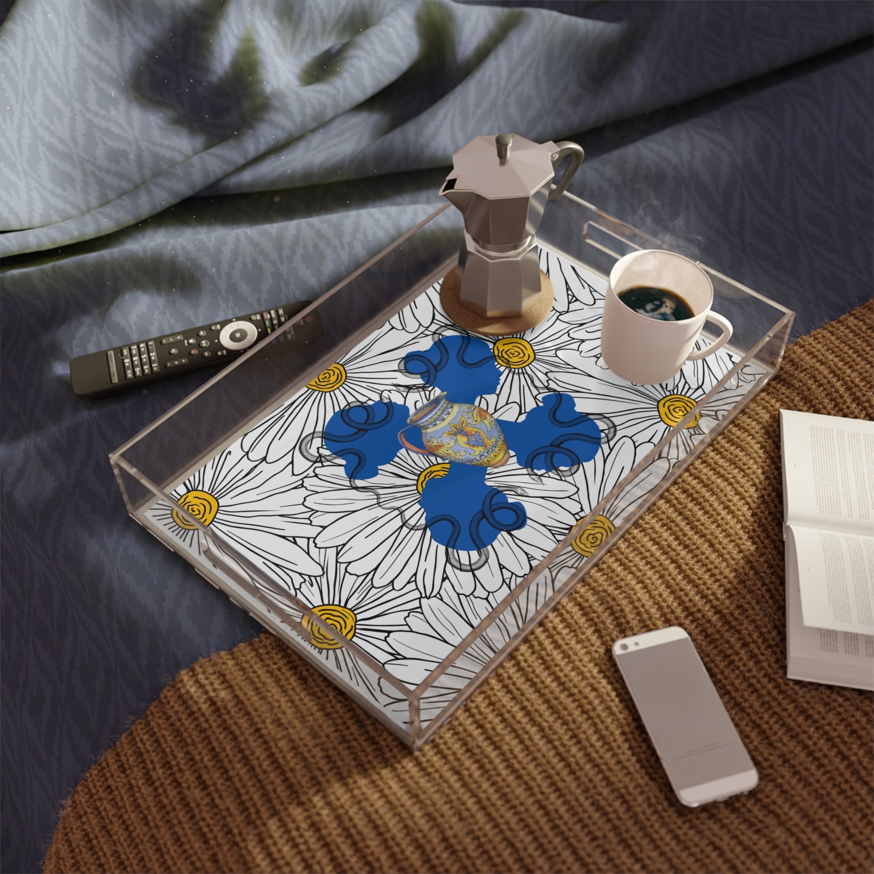 Daisy ladies in blue acrylic tray on a round jute rug — moka pot and coffee cup, navy linen, books