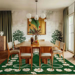 A stylish dining room featuring a hand-tufted wool rug with a vibrant green background adorned with white floral and snake patterns. This large area rug adds a boho touch to the space, complementing the wooden dining table and chairs. Perfect for bedrooms or large living rooms, this rug enhances the room's aesthetics with its intricate design.