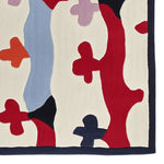 A vibrant hand-tufted area rug with an abstract design featuring bold colors like red, blue, and orange on a cream background. Perfect for adding a contemporary touch to living room spaces, this wool rug offers a unique blend of style and comfort.