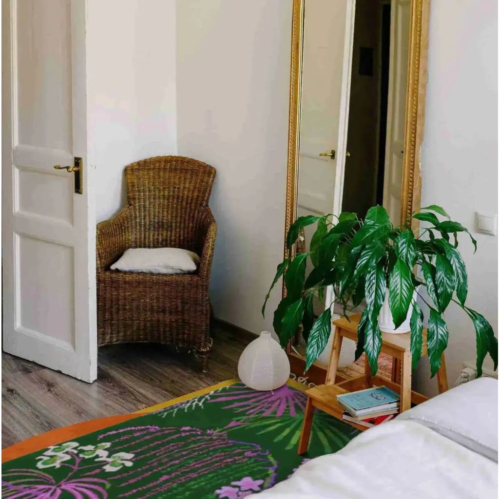 A cozy living room setting featuring a Wild Bloom Elegant Hand Tufted Wool Area Rug. The vibrant design of the wool rug complements the natural decor, with a wicker chair, a large mirror, and a lush plant adding to the room's inviting atmosphere. Perfect for office or living room use.