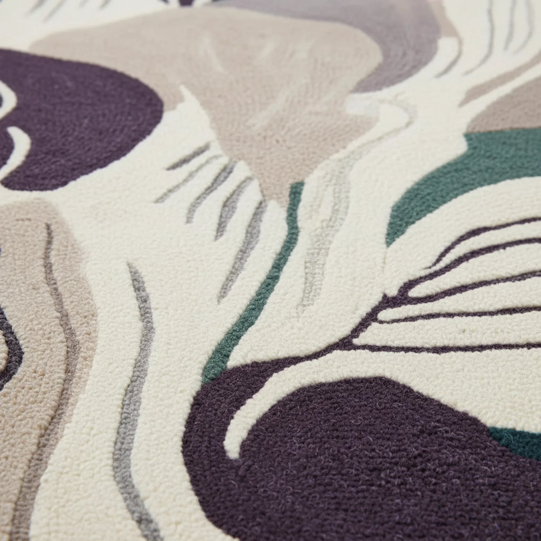 Close-up of a textured rug with abstract leaf patterns in purple, green, and beige.