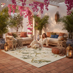 Woman sitting on a patio with a floral rug and plants