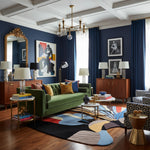 Living room with a green sofa, colorful rug, and decorative elements.