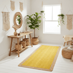 Nest living room with wooden console table, yellow jute rug, and decorative plants.
