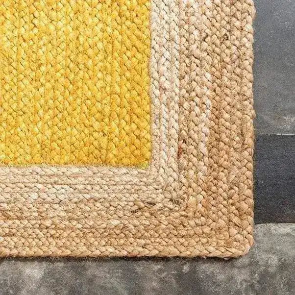 Close-up view of a yellow rectangular jute rug, perfect for adding a boho touch to your bedroom. This area rug features a vibrant yellow center with natural jute braiding around the edges, making it an ideal choice for rugs for bedroom spaces.