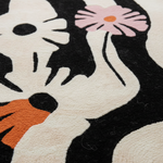 Close-up of a rug with a stylized design of a cat holding a flower.