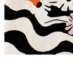 The Zebra Bloom Hand Tufted Wool Rug showcases a striking abstract design, featuring bold black and white stripes with hints of pink and orange floral accents. This contemporary area rug is perfect for adding a touch of modern elegance to your living room, crafted from high-quality wool for a luxurious feel.