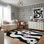 Modern nursery room with black and white geometric wallpaper, abstract art, and a patterned floral contemporary wool rug.