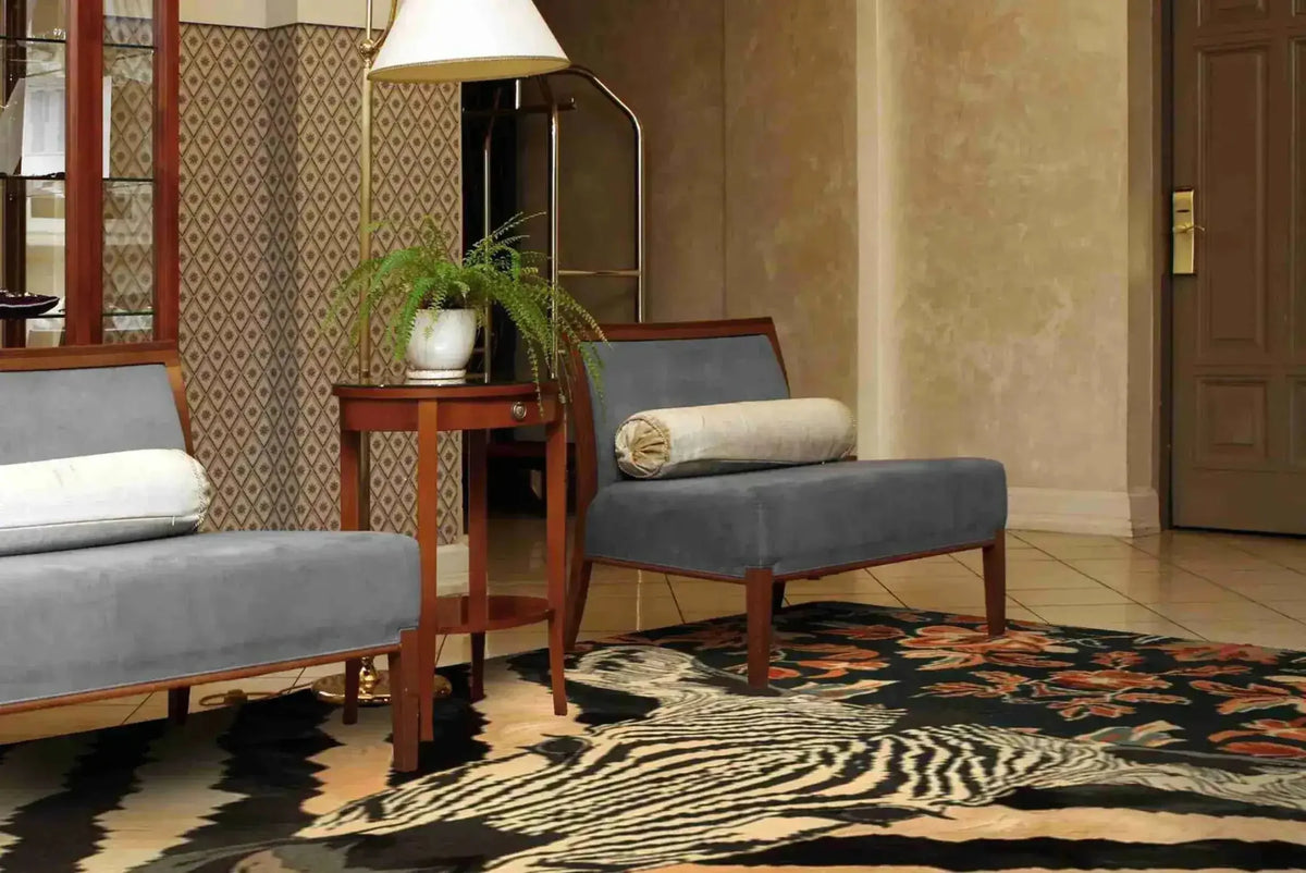 A stylish Zebra Fusion Hand Tufted Area Rug placed in a cozy dining room setting. This large wool rug features an eye-catching zebra pattern with vintage floral details, complementing the elegant furniture and creating a warm, inviting atmosphere perfect for under a dining table.