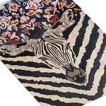 Angled close-up of the zebra rug, striped head meeting a coral-and-navy floral panel