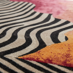 Close-up of a rug with black and white wavy pattern and orange triangle