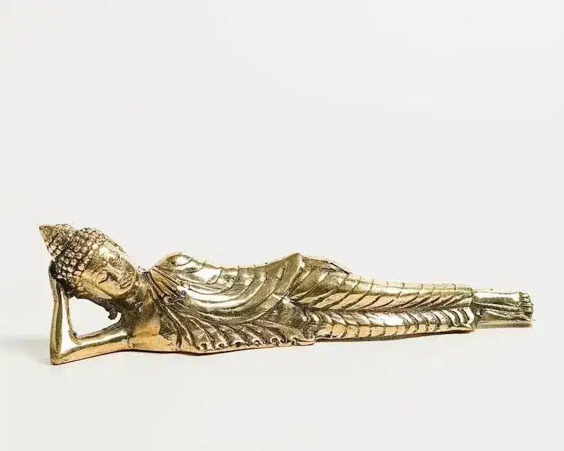 Gold-brass reclining Buddha figurine, front-left angled view, head propped on arm, robe detail visible