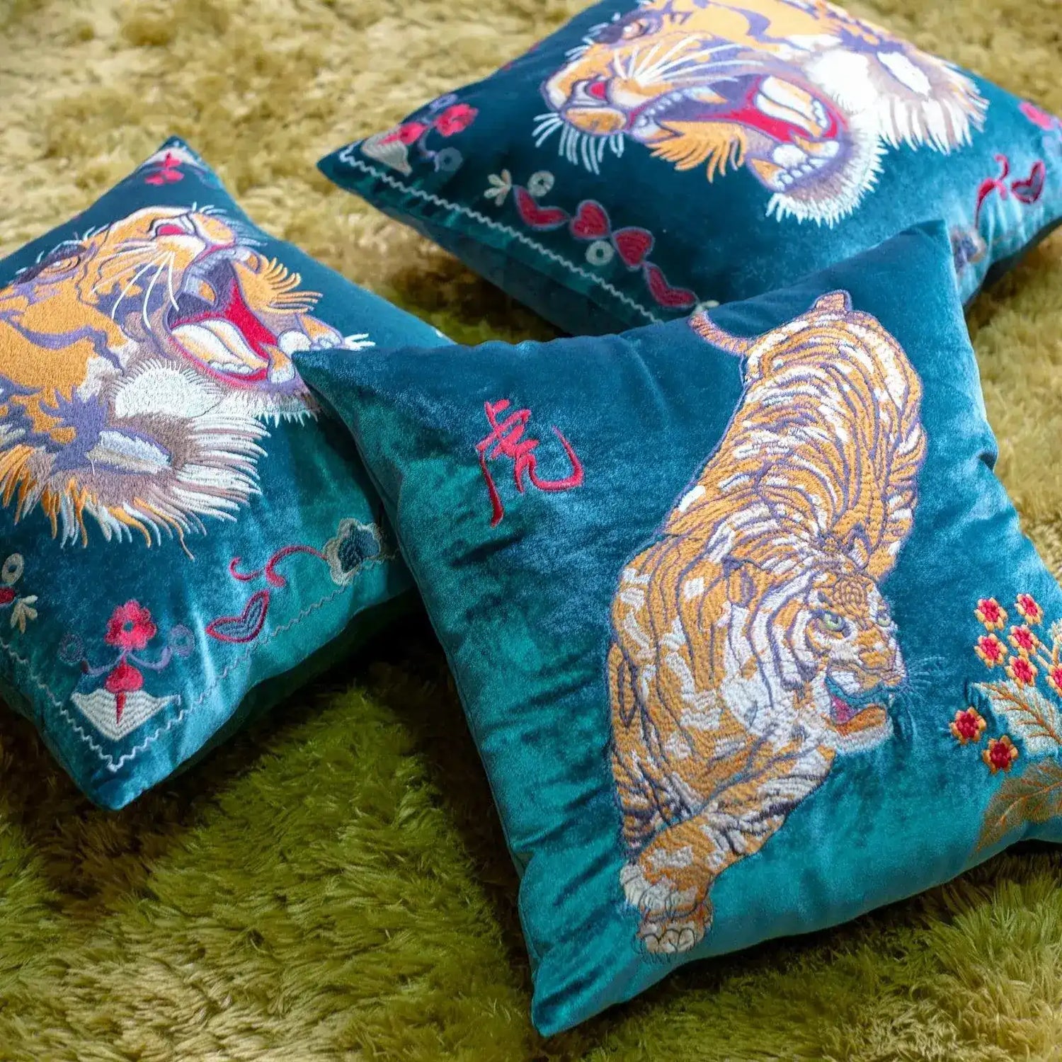Embroidered decorative throw pillows featuring vibrant tiger designs on a green background, perfect for home decor.