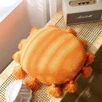 Round orange decorative throw pillow with tassels, perfect for adding a pop of color to any space.
