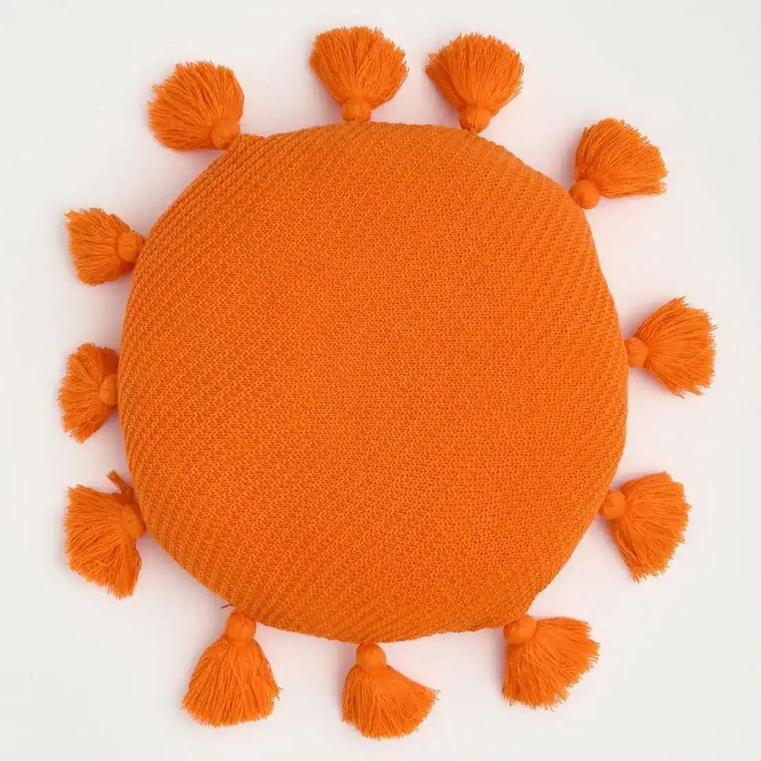 Round orange decorative throw pillow with tassels, perfect for adding a pop of color to any room decor.