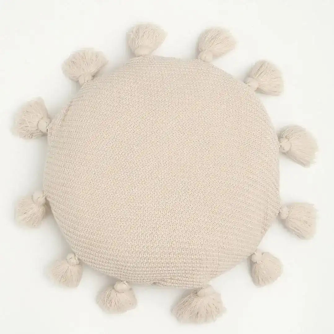 Round decorative throw pillow with tassels in a soft beige color, perfect for adding a cozy touch to any decor.