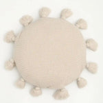Round decorative throw pillow with tassels in a soft beige color, perfect for adding a cozy touch to any decor.