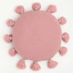Round decorative throw pillow with tassels in soft pink color, perfect for adding a touch of charm to any living space.