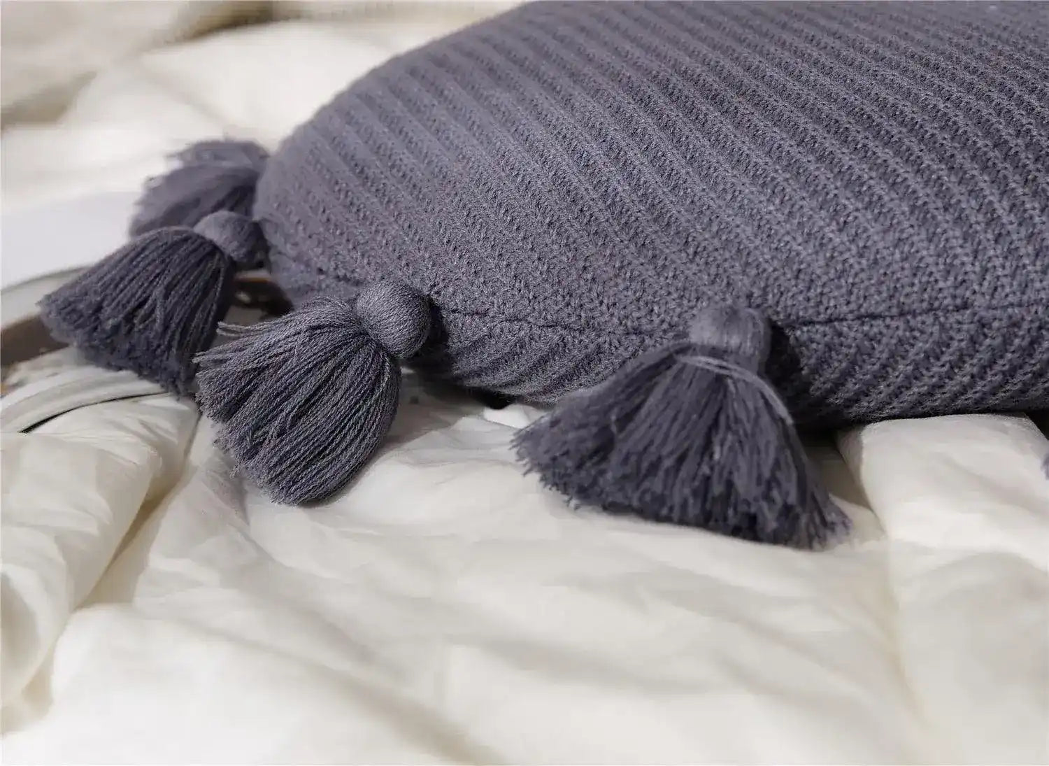 Round decorative throw pillow with tassels, featuring a textured gray fabric, perfect for home decor and comfort.