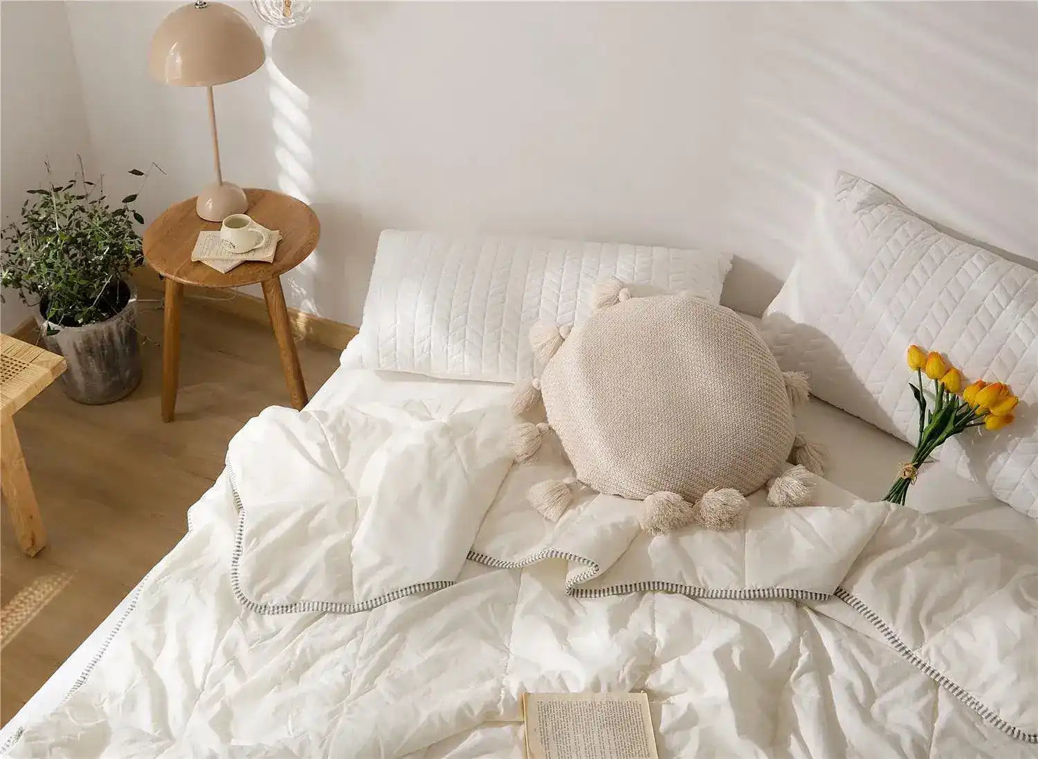 Round tassel decorative throw pillow on a cozy bed with white bedding, adding a touch of style and comfort to the bedroom decor.